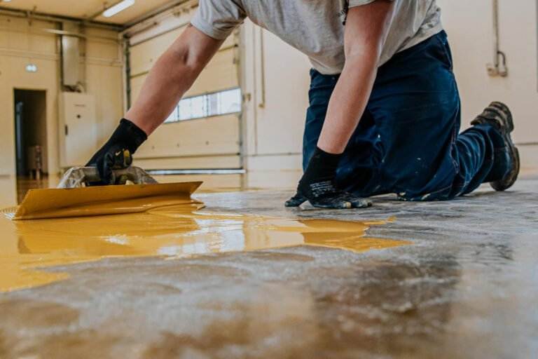 worker coating floor with selfleveling epoxy resin industrial workshop