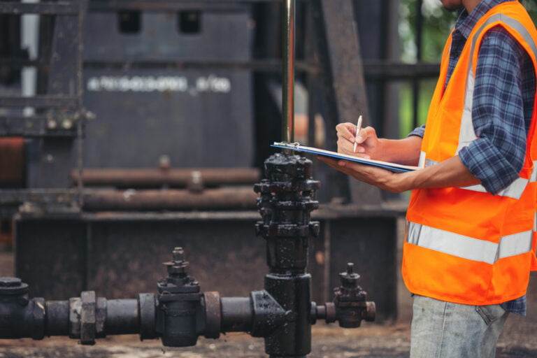 workers standing and checking beside working oil pumps.