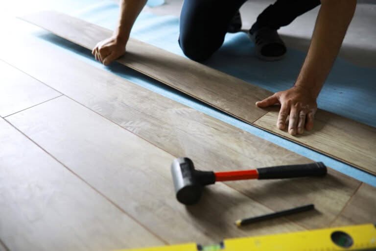 installing laminated floor detail man hands blue wooden tile white foam base layer small pile with more tiles background