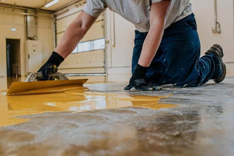 worker coating floor with selfleveling epoxy resin industrial workshop